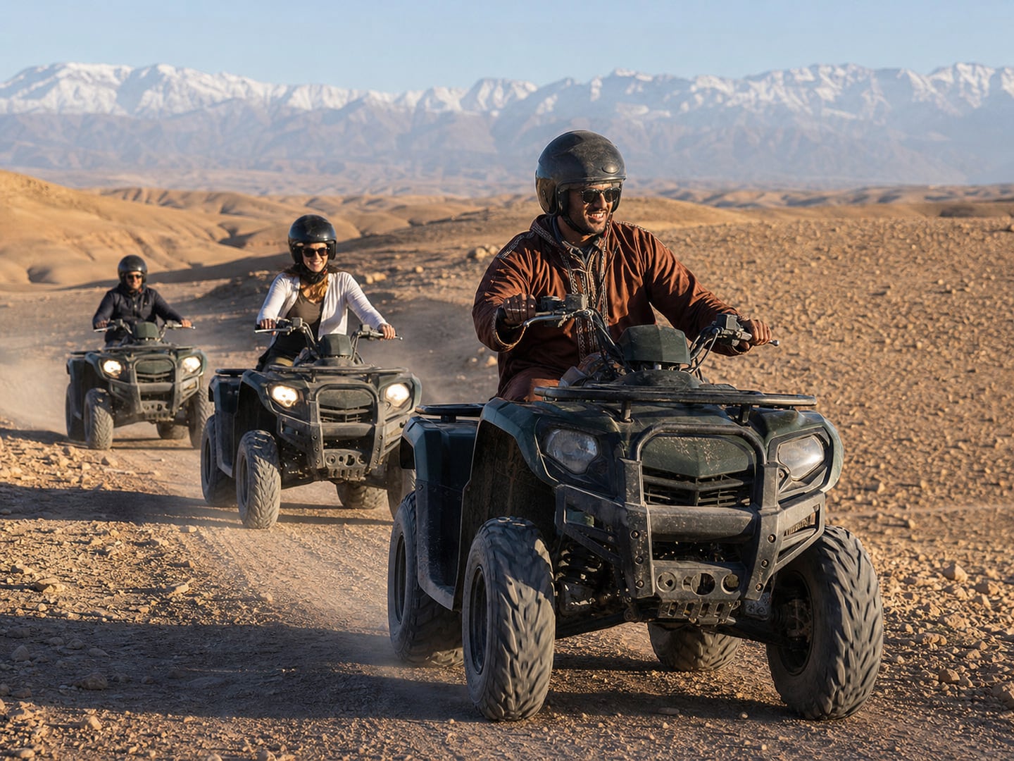 Helmeted travellers riding quad bikes on a rocky Agafay Desert trail